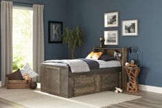 a bedroom with blue walls and white carpeted flooring has a bed frame made out of wood