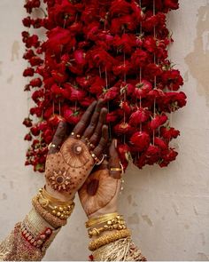 two hands touching each other with red flowers in the background