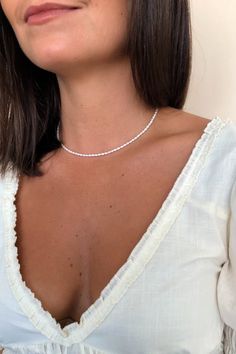 This dainty strand of natural white freshwater rice pearls goes with everything from t-shirts to dresses!  Pearls measure approx. 2.5 mm.  All components are 14k gold filled or sterling silver and are considered lifetime quality with proper care. This style makes the perfect gift and looks great layered!Closure: spring ring claspMaterials: Sterling Silver or 14k Gold FilledMeasures 14" - 16" (adjustable) in lengthHandmade in New York Tiny Gold Necklace, Affordable Fine Jewelry, Pearl Necklace Choker, Dainty Pearl Necklace, Baguette Necklace, Elizabeth Jewelry, Pearl Jewelry Gift, Rice Pearls, Pearl Collar