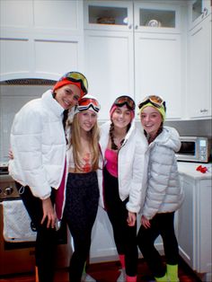 three girls and one boy are standing in the kitchen