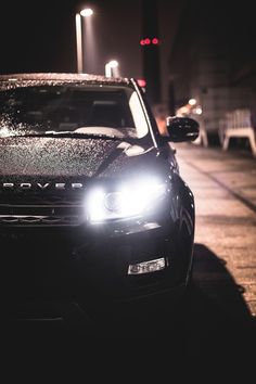 a car is parked on the side of the road at night with its lights on