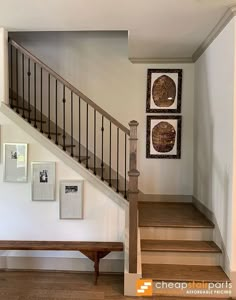 the stairs are made of wood and have metal railings on each handrail, along with pictures hanging on the wall