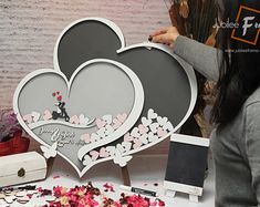 a woman is cutting out a heart shaped card with flowers on the table next to it