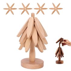 a wooden toy tree with four stars on it and a hand reaching for the star