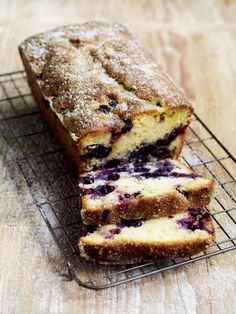 a loaf of blueberry bread sitting on top of a cooling rack with slices cut out