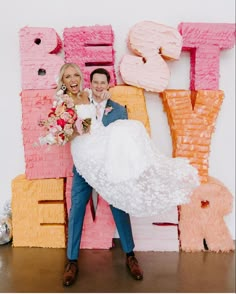 a bride and groom posing in front of giant letters that spell out the word love