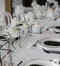 the table is set with white flowers and place settings for guests to sit down at