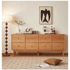 a living room with a wooden dresser next to a lamp