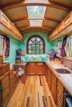 the inside of a tiny home with wood flooring and green walls, along with wooden cabinets