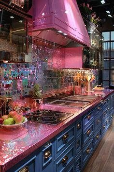 a pink kitchen with blue cabinets and counter tops is pictured in this image, there are fruit on the plate next to the stove