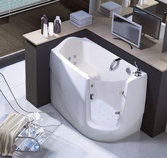 a bathroom with a large jacuzzi tub next to a window and television on the wall