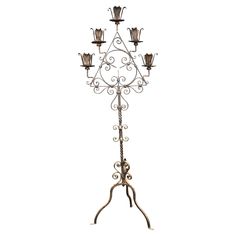 a wrought iron candle stand with four candles on it's legs and one light fixture attached to the base