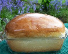 a loaf of bread sitting on top of a green cloth next to blue and purple flowers