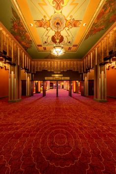 an empty ballroom with red carpet and chandeliers on either side of the room