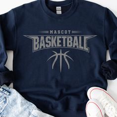 a blue sweatshirt with the words mascot basketball on it and two pairs of shoes next to it