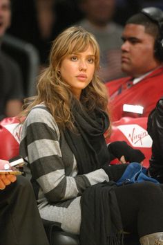 a woman sitting in the stands at a basketball game