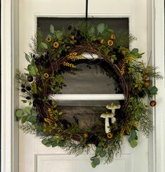 a wreath hanging on the front door of a house with cross and sunflowers