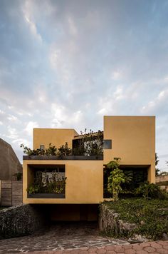 the house is made out of concrete and has plants growing on it