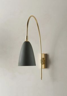 a wall light that is on the side of a wall with a gray shade hanging from it's arm