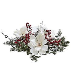 white flowers and greenery are arranged in a glass vase with red berries on the rim