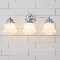 three light bathroom fixture with white tiles on the wall