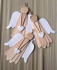 wooden spoons with white hearts and angel wings hanging from strings on a brown table