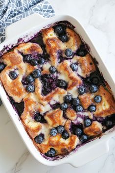 a casserole dish with blueberries and cream in it on a marble counter top