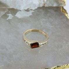 14K Yellow Gold Garnet and Diamond Ring, garnet rectangular offset 4 round diamond side stones, .25 inch across, Ring size 6.75, Circa 1970, 3.4 grams SKU # BB256R27 Most rings are sizable for a small fee. If the ring you are considering is the incorrect size contact us for a quote. This listing contains photographs of the actual item you will receive. Our items are in excellent condition with little or no signs of wear and many are one of a kind pre-owned estate finds. Please look closely at th Elegant Multi-stone Rectangular Rings, Elegant Rectangular Multi-stone Rings, Modern Brown Jewelry For Anniversary, Rectangular Three Stone Diamond Jewelry, Three Stone Rectangular Diamond Jewelry, Modern Multi-stone Rectangular Jewelry, Classic Brown Rectangular Jewelry, Classic Multi-stone Princess Cut Rings, Classic Princess Cut Multi-stone Rings