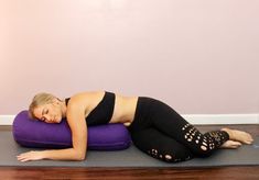 a woman laying on top of a purple pillow in the middle of a yoga pose