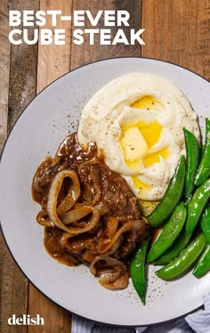 a white plate topped with meat and veggies next to an egg on top of mashed potatoes