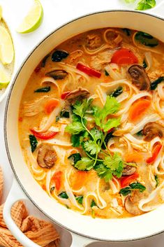 a bowl of soup with noodles, mushrooms and cilantros on the side