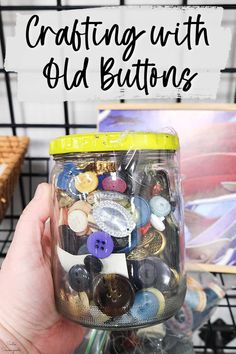 a hand holding a jar full of buttons with the words crafting with old buttons