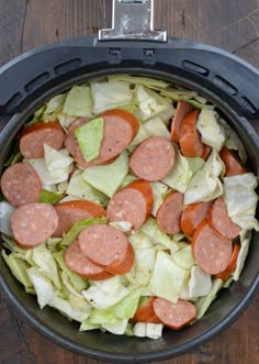 a bowl filled with lettuce and hotdogs on top of a wooden table