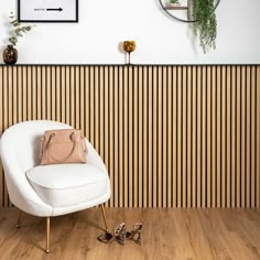 a white chair sitting in front of a wooden wall with a clock on it's side