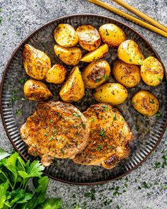 two pieces of pork chops and potatoes on a plate next to some parsley