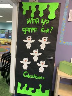 a classroom door decorated for halloween with ghostes and green writing on it's side