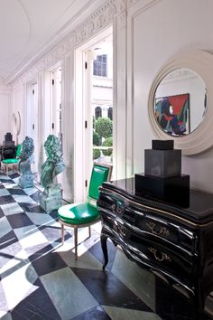 a room with black and white checkered flooring and green chairs in the corner