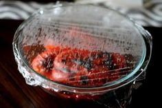 a glass bowl filled with strawberries on top of a wooden table