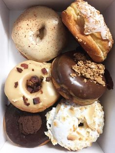 a box filled with assorted donuts on top of each other in different flavors