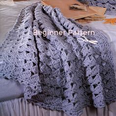 there is a crocheted blanket on top of the bed with hats and books