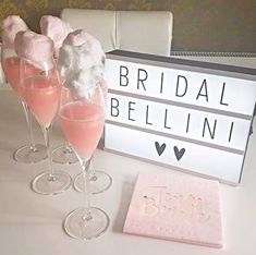 two champagne flutes with marshmallows in them next to a sign that says bridal bellini