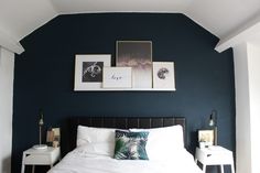 a white bed sitting in a bedroom next to a wall with pictures hanging on it