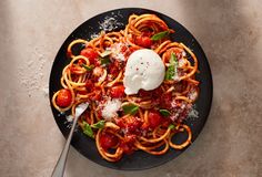 a plate of spaghetti with tomato sauce and parmesan cheese on top, next to a fork