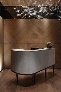 a modern reception area with wood paneling and lights hanging from the ceiling above it