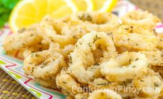 some fried food on a plate with lemon wedges and parsley in the background