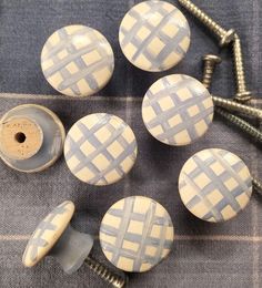 four white and blue checkered ceramic knobs with screws on a gray cloth