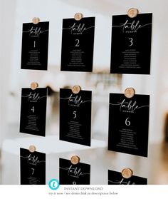 black and white wedding seating cards hanging on a wall with wooden buttons in the middle