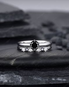 a black and white diamond ring sitting on top of a rock