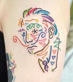 a colorful tattoo on the back of a woman's left arm, depicting an image of a clown