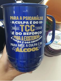 a person holding a blue coffee cup with words written on the bottom and inside it